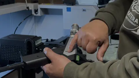 Ricos Hände justieren den Laserkopf der Maschine, er trägt sein Marke-Eigenbau-Hoodie