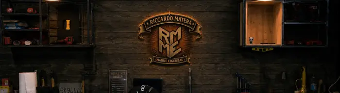 Ricos Werkstattwand mit beleuchtetem RMME-Vintage-Emblem über der Werkbank