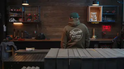 Rico von hinten in der Werkstatt im olivgrünen Hoodie mit großem Riccardo-Matera-Marke-Eigenbau-Rückenprint