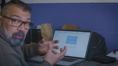 Rico erklärt am Laptop die CAD-Konstruktion des Schlitzers in Fusion 360, auf dem Bildschirm die geschlitzten Grillroste